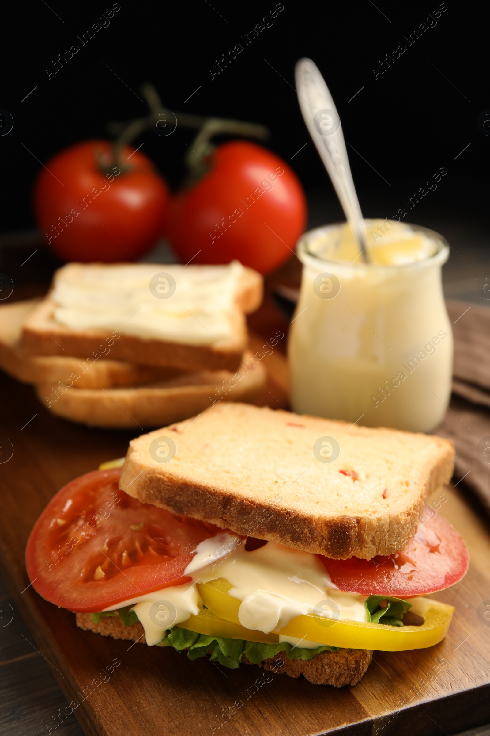 Photo of Delicious sandwich with vegetables and mayonnaise served on wooden board, closeup