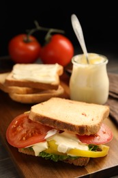 Delicious sandwich with vegetables and mayonnaise served on wooden board, closeup