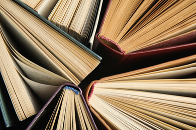 Photo of Many different hardcover books on dark background, top view