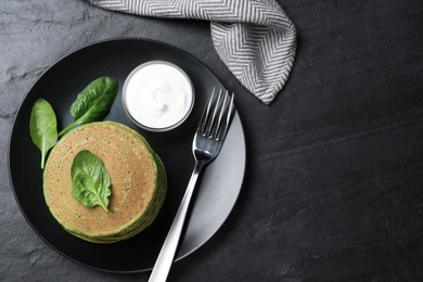 Photo of Tasty spinach pancakes served on black table, flat lay