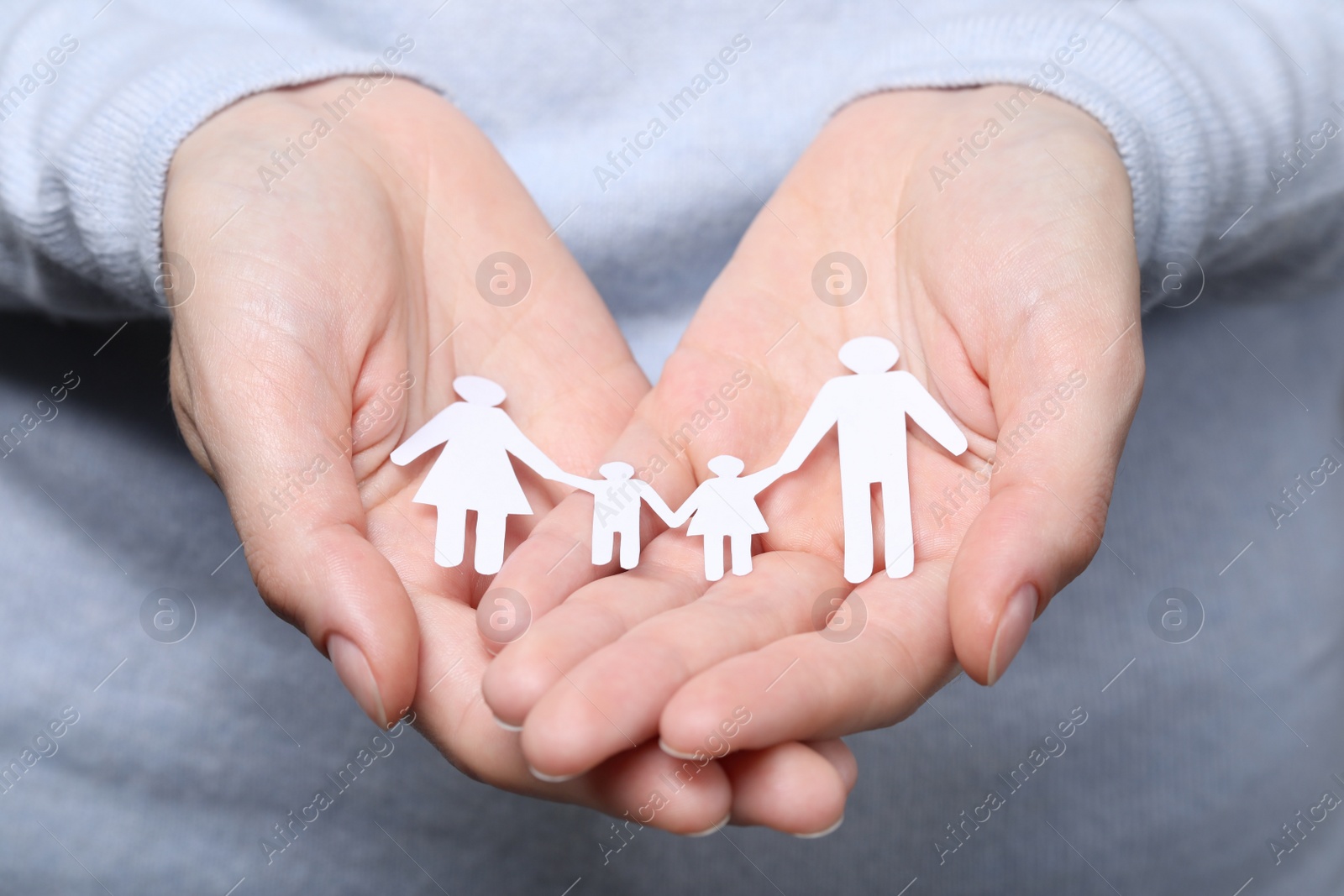 Photo of Woman holding paper family figures, closeup. Insurance concept