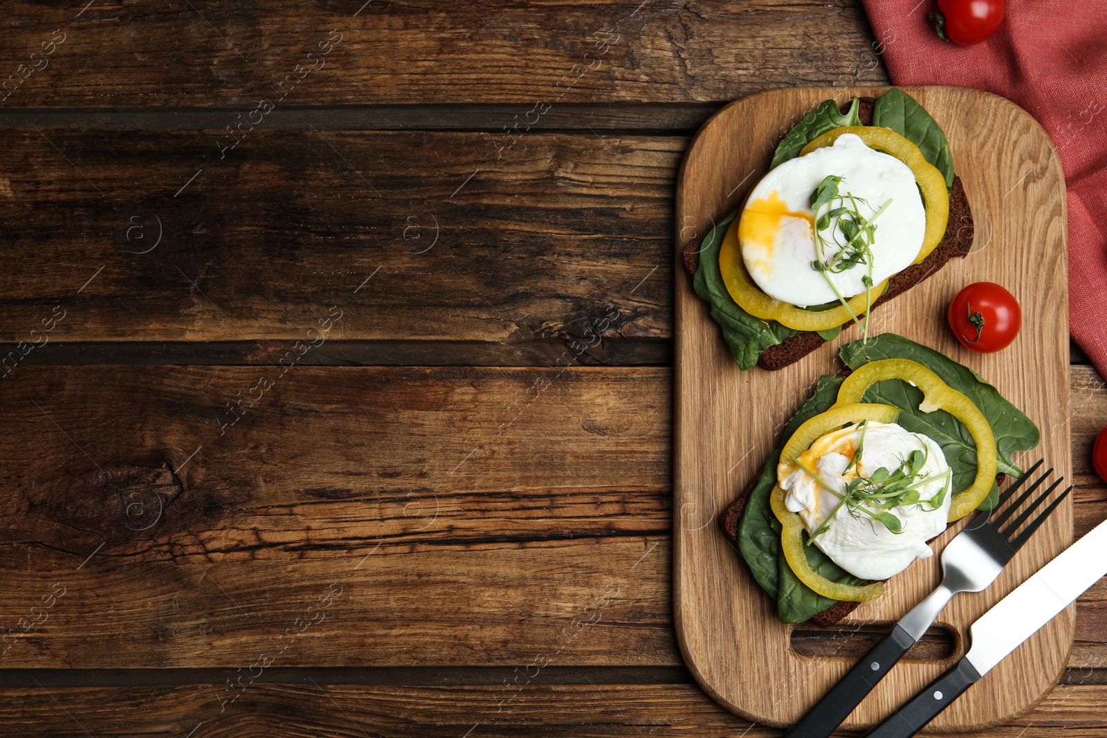 Photo of Delicious poached egg sandwiches served on wooden table, flat lay. Space for text
