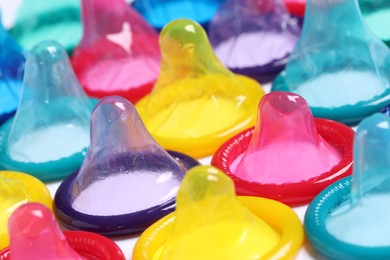 Photo of Colorful condoms on white background, closeup view. Safe sex