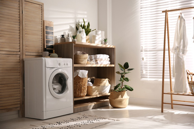 Photo of Modern washing machine and shelving unit in laundry room interior