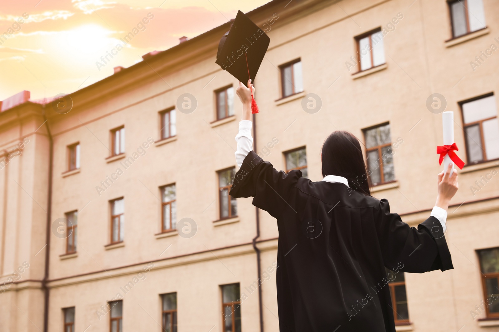 Photo of Student with diploma after graduation ceremony outdoors, back view. Space for text