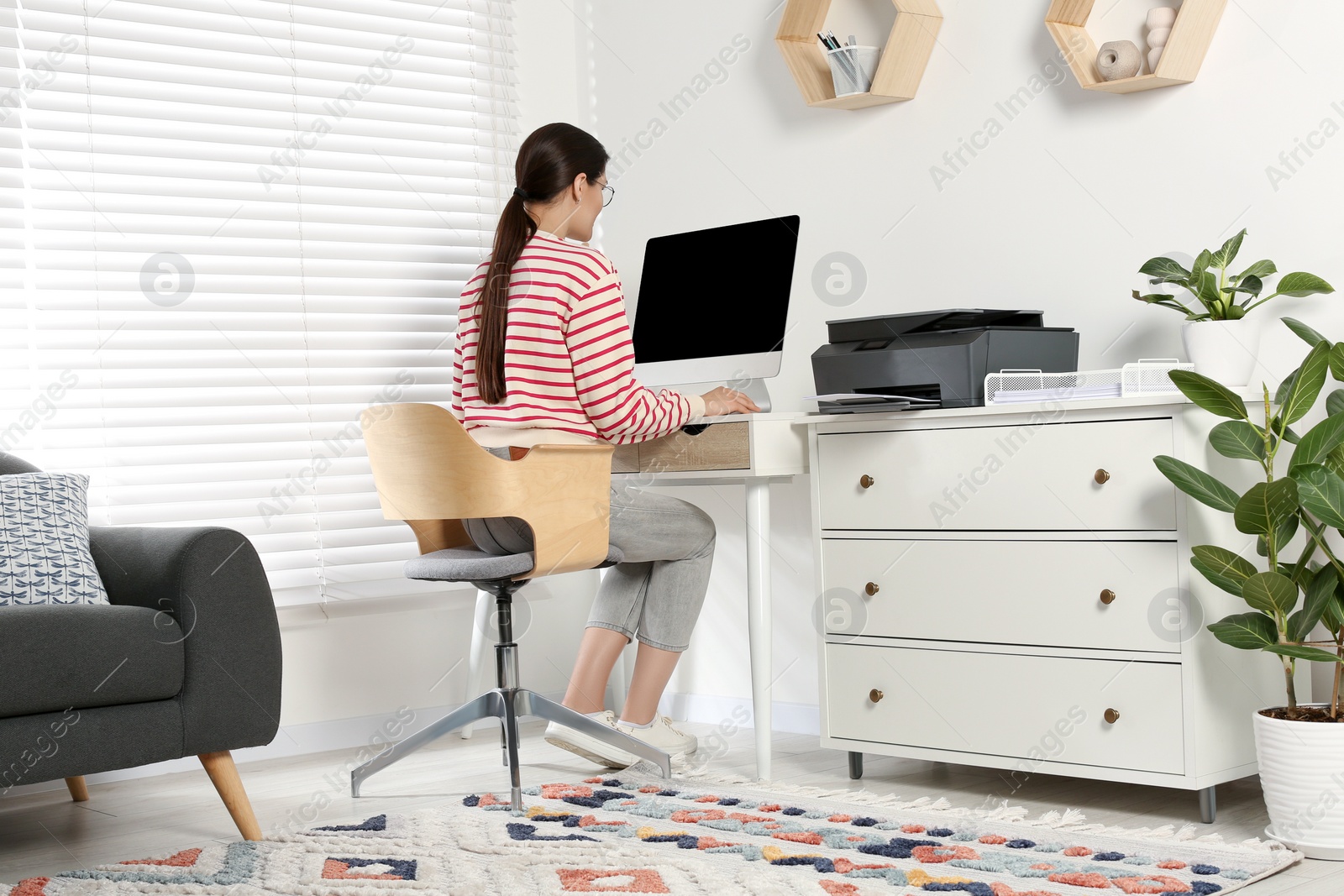 Photo of Woman using modern printer at workplace indoors