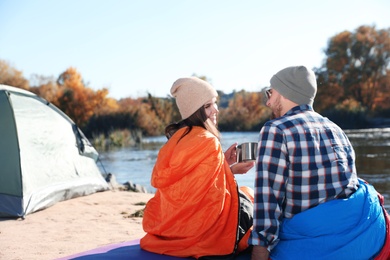 Photo of Campers sitting in sleeping bags on wild beach. Space for text