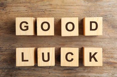 Photo of Cubes with phrase GOOD LUCK on wooden background, flat lay