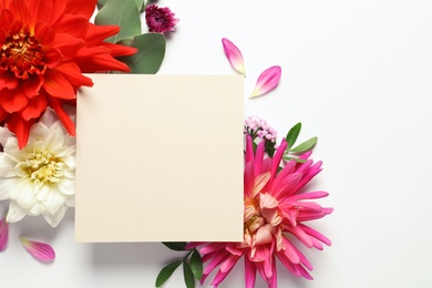 Flat lay composition with beautiful dahlia flowers and blank card on white background