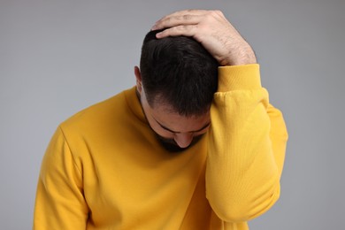Photo of Sad man grabbing his head on light grey background