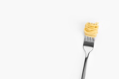 Photo of Fork with tasty pasta on white background, top view. Space for text