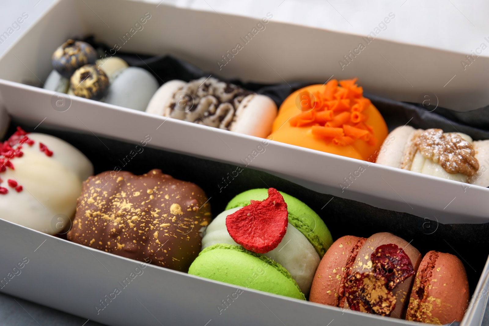 Photo of Cardboard box with delicious sweet macarons, closeup
