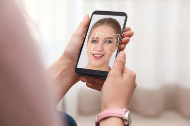 Image of Woman using smartphone with facial recognition system indoors, closeup. Biometric verification