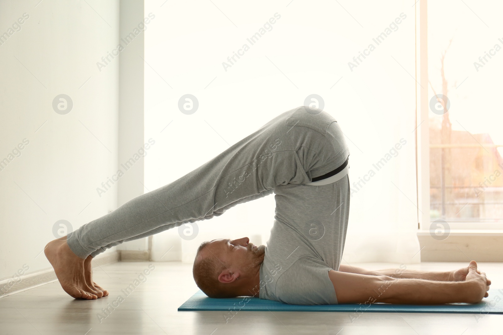 Photo of Sporty man practicing yoga indoors