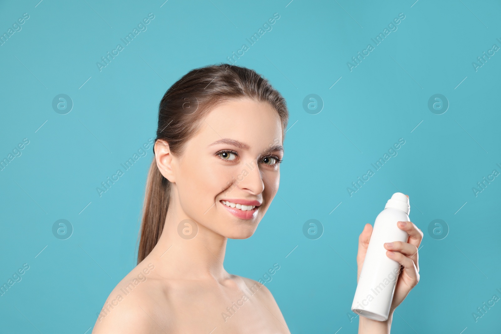 Photo of Young woman with bottle of thermal water on color background. Cosmetic product