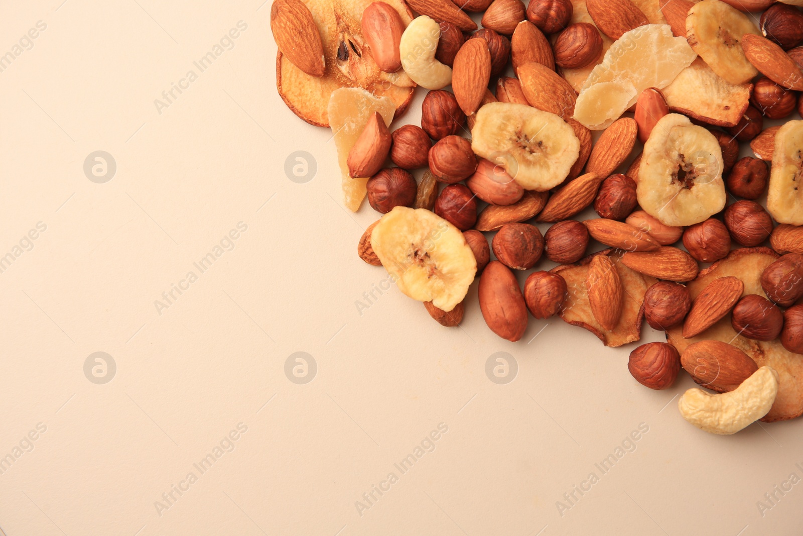 Photo of Different tasty nuts and dried fruits on beige background, flat lay. Space for text