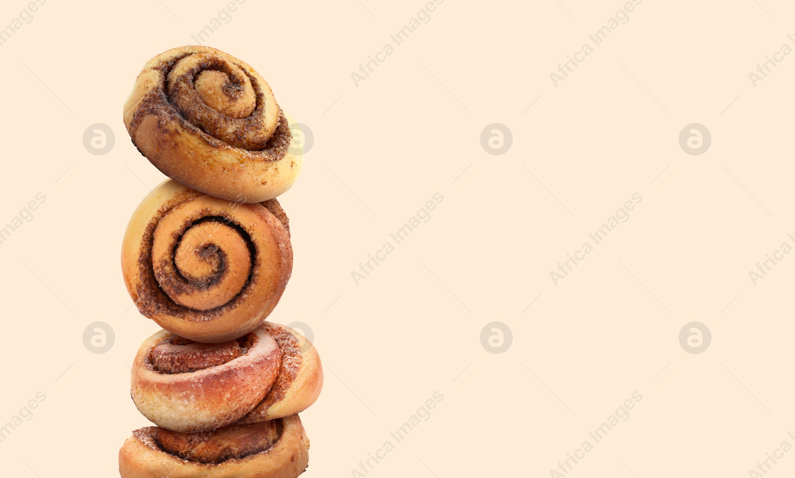 Image of Cinnamon rolls balancing on beige background. Banner design with space for text