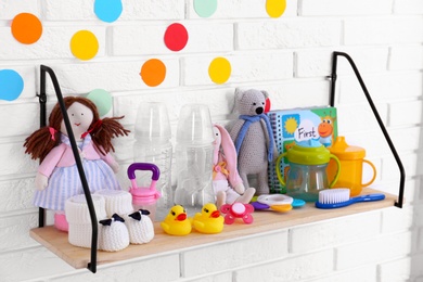 Baby accessories on shelf near white brick wall