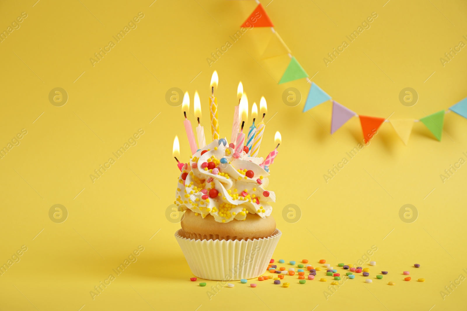 Photo of Birthday cupcake with candles on yellow background