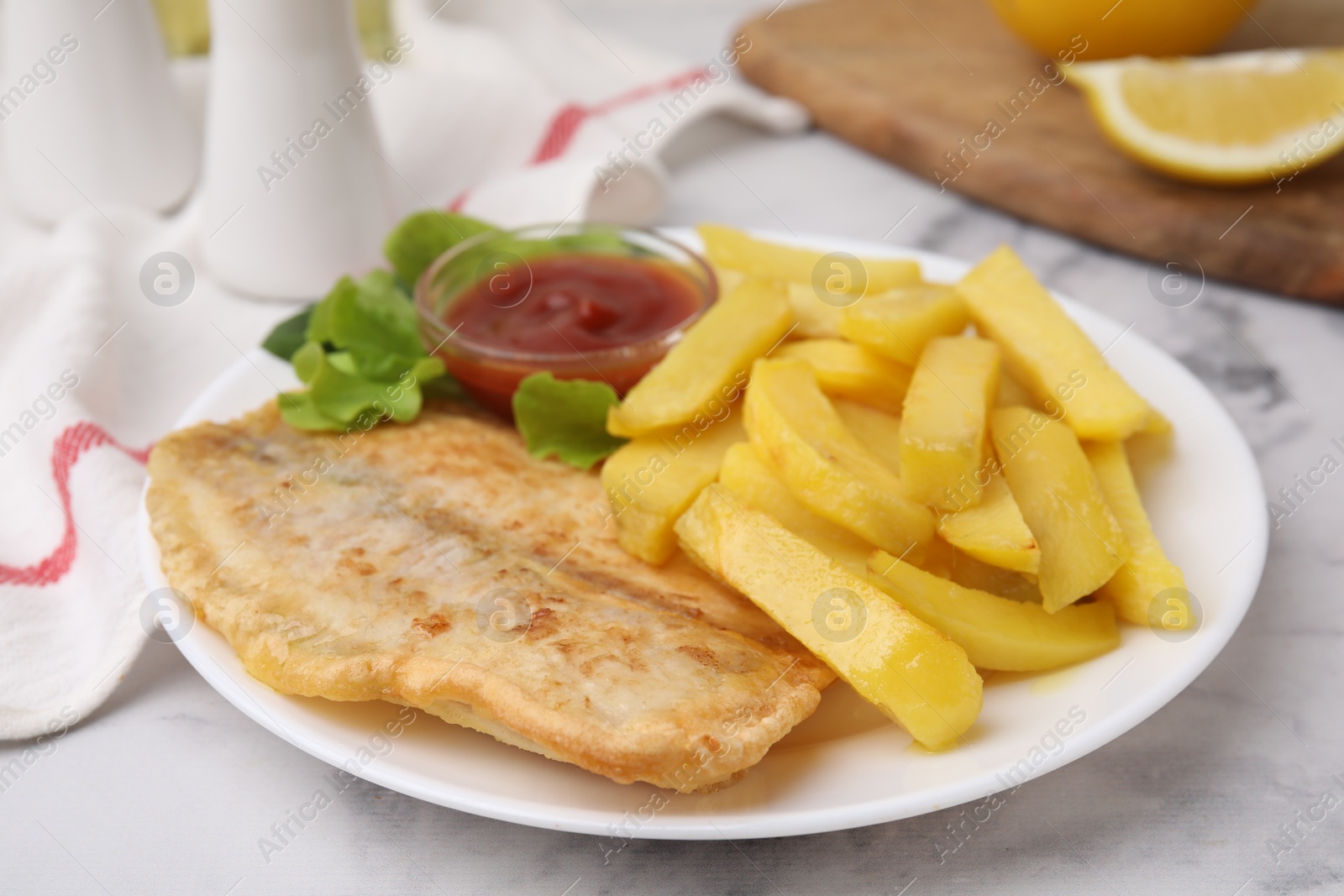 Photo of Delicious fish and chips with ketchup and lettuce on light table, closeup