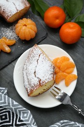 Piece of delicious homemade yogurt cake with powdered sugar and tangerines on gray table, flat lay