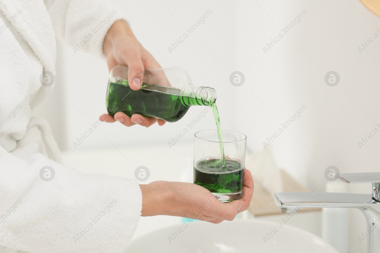 Photo of Young man using mouthwash in bathroom, closeup