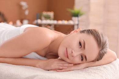 Photo of Young woman lying on massage table in spa salon