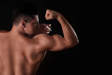 Photo of Athletic man injecting himself on black background. Doping concept