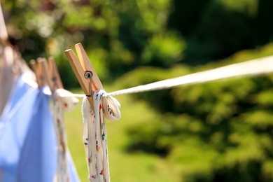 Clean clothes drying in garden, closeup. Focus on clothespin