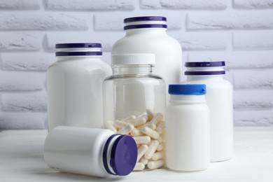 Photo of Medical bottles with pills on white wooden table, closeup