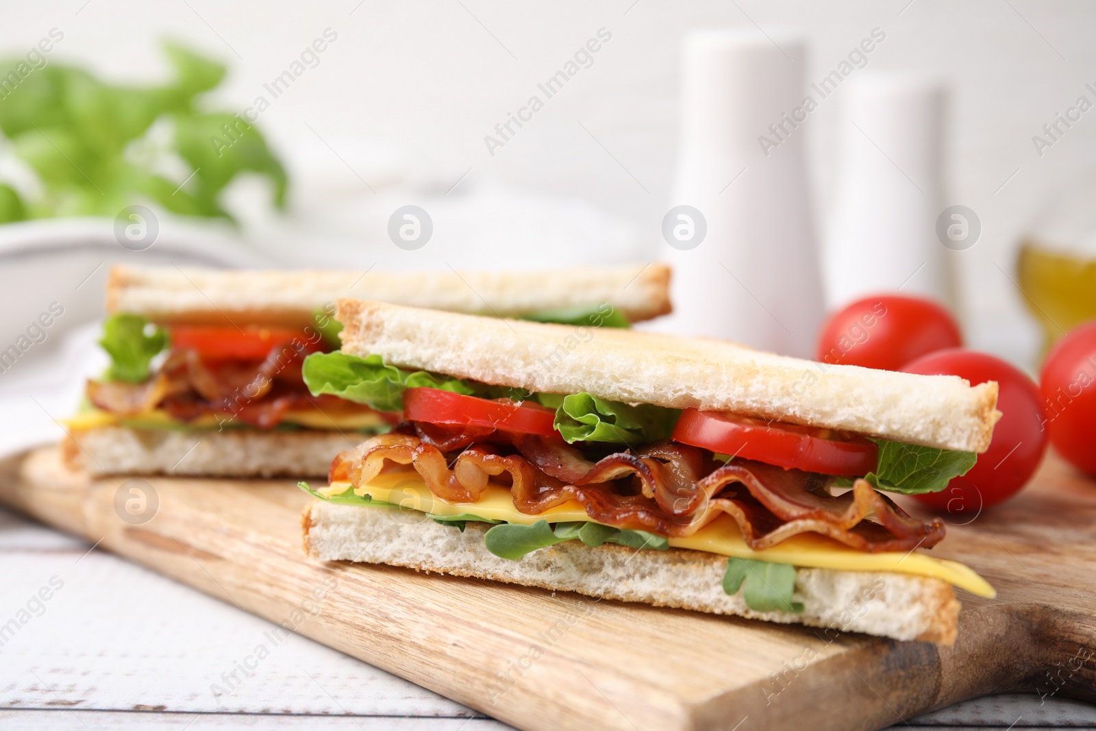 Photo of Delicious sandwiches with fried bacon on wooden rustic table, closeup