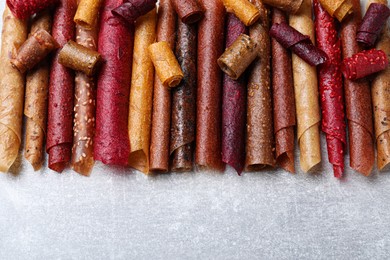Photo of Delicious fruit leather rolls on grey table, flat lay