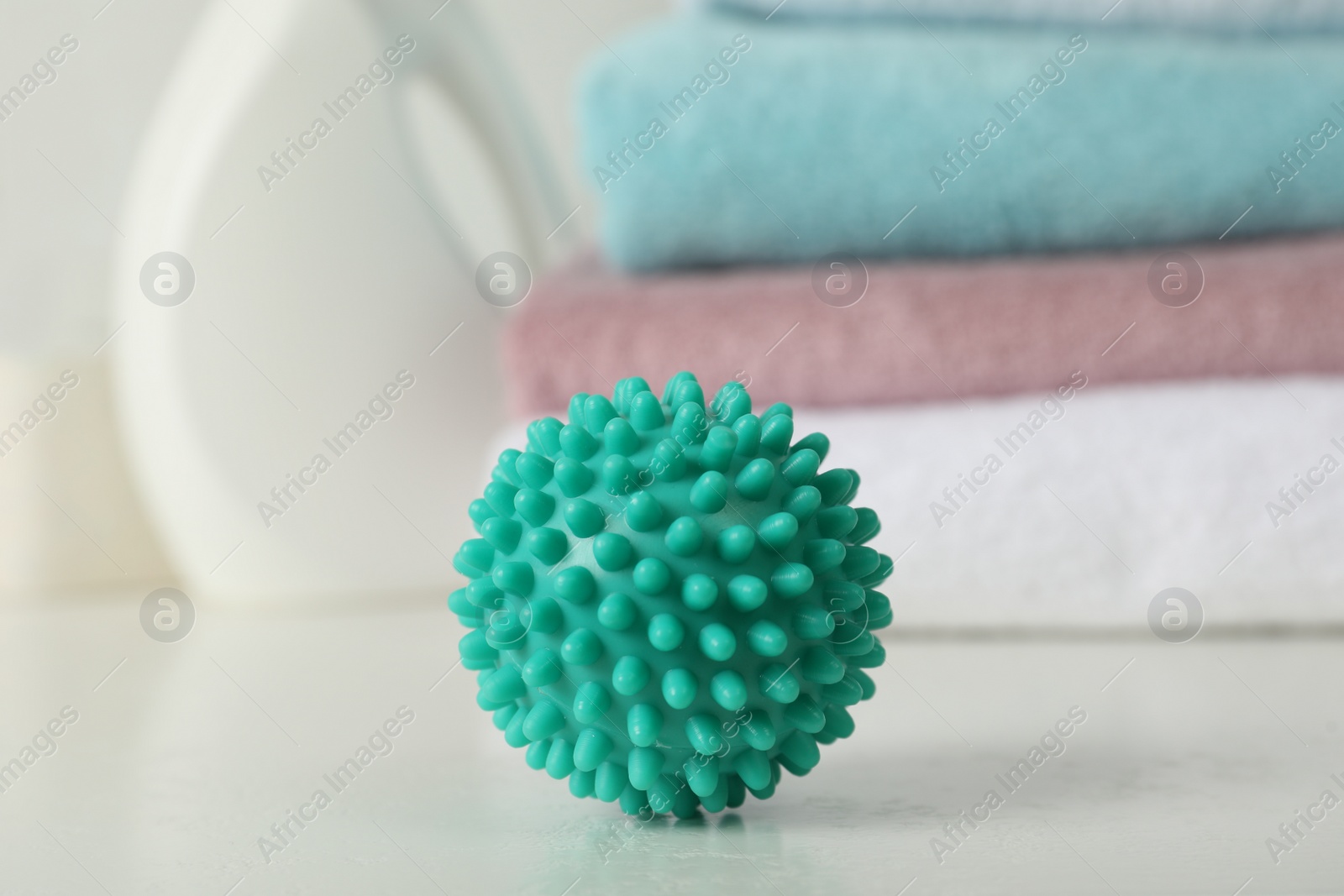 Photo of Turquoise dryer ball on white table, closeup