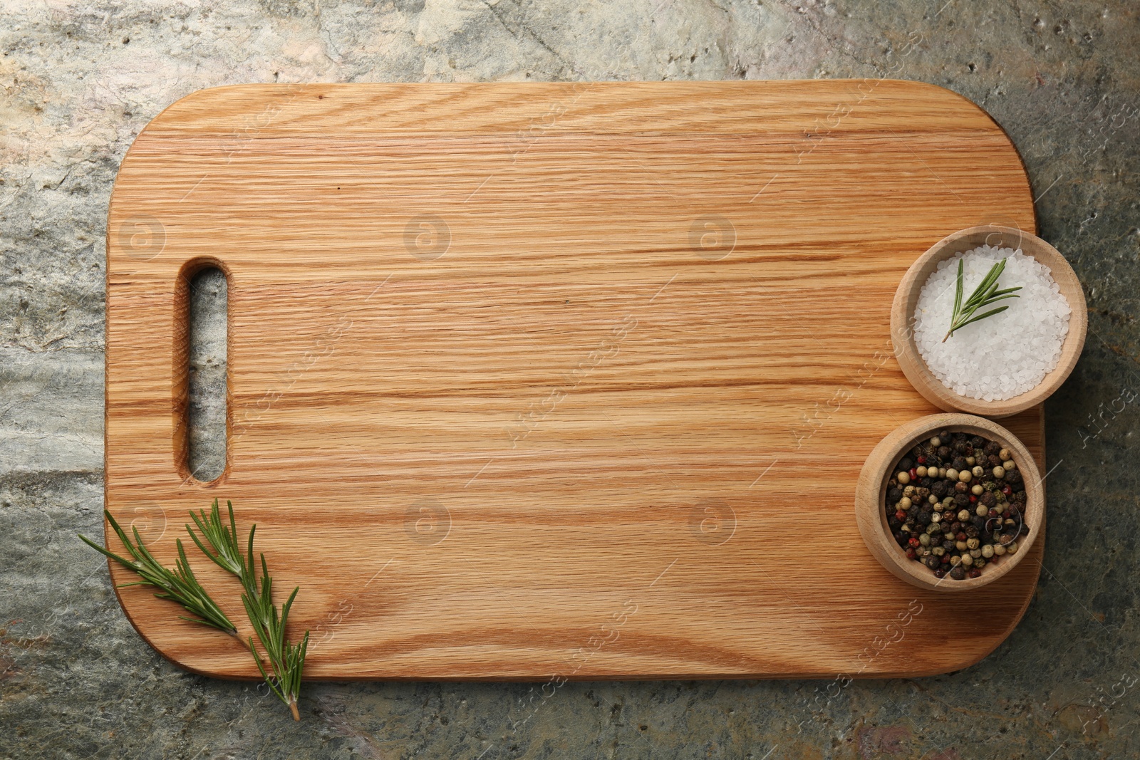 Photo of Wooden cutting board and spices on textured table, top view. Space for text