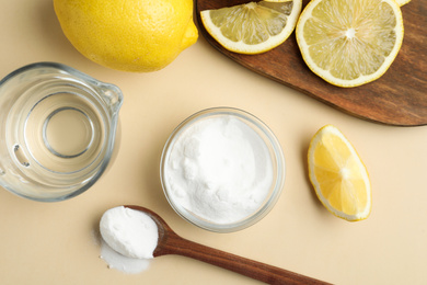 Photo of Baking soda, lemons and vinegar on beige background, flat lay