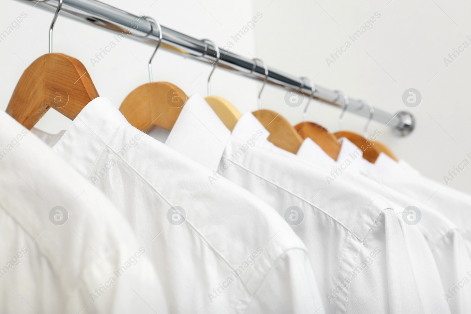 Photo of Rack with clean clothes after dry-cleaning on hangers