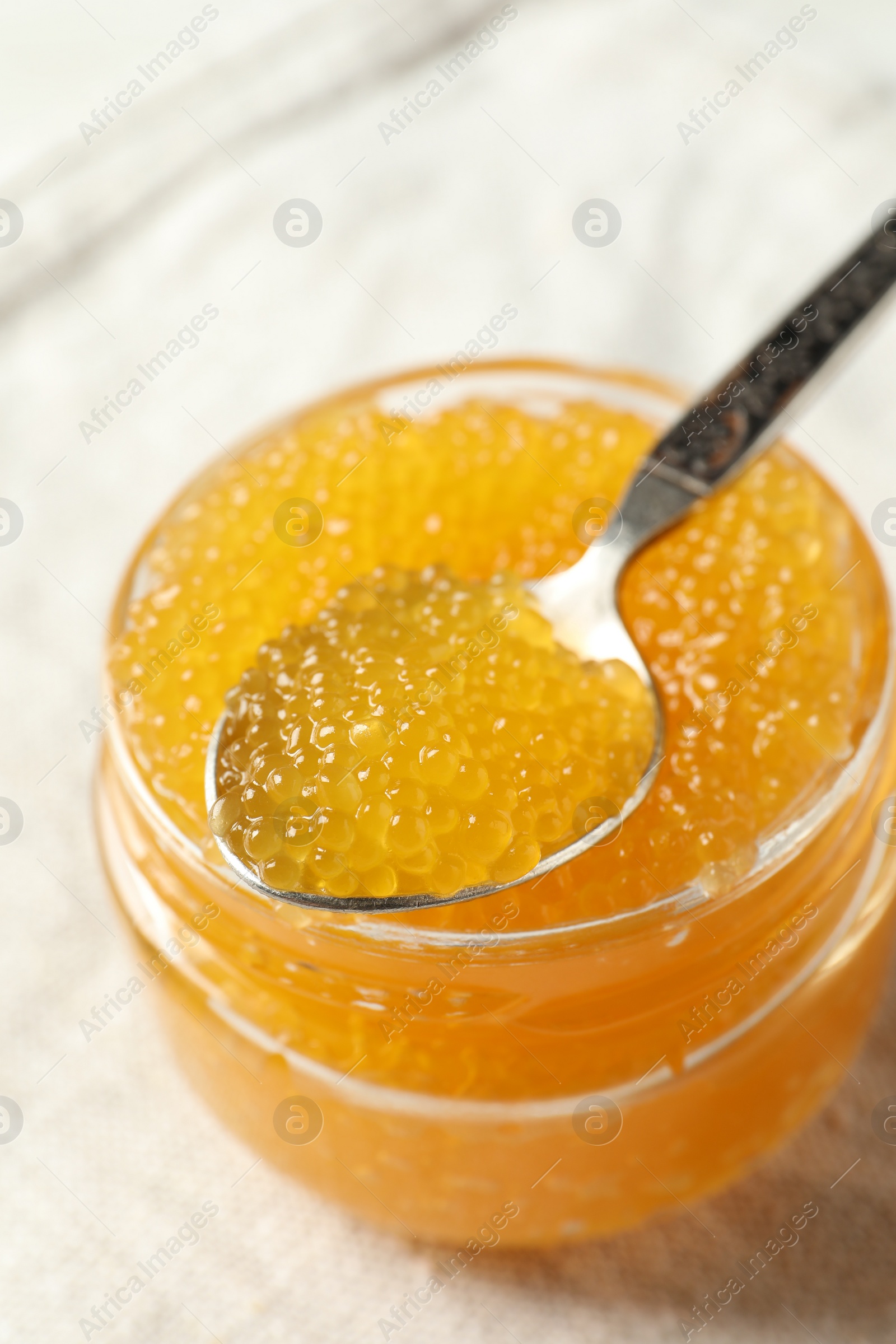 Photo of Fresh pike caviar in glass jar and spoon on table, closeup