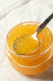 Fresh pike caviar in glass jar and spoon on table, closeup