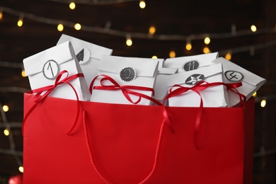 Photo of Set of gifts in red bag against blurred lights, closeup. Christmas advent calendar