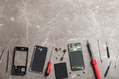 Disassembled mobile phone and repair tools on table, flat lay. Space for text