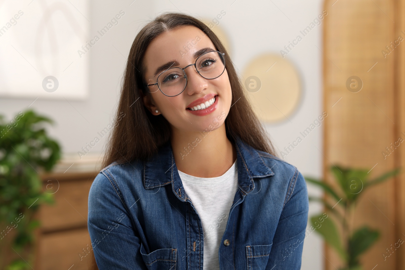 Photo of Portrait of beautiful young woman with glasses indoors. Attractive lady smiling and looking into camera