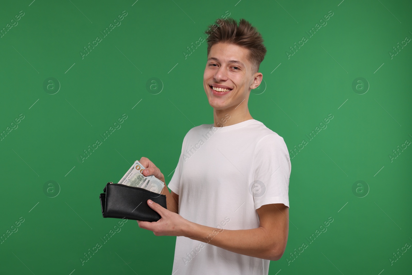 Photo of Happy man putting money into his wallet on green background