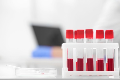 Test tubes with blood samples and scientist working on computer in laboratory