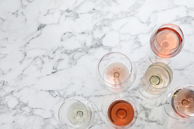 Photo of Different glasses with wine on marble background, flat lay. Space for text