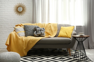 Photo of Stylish living room interior with soft pillows and yellow plaid on sofa