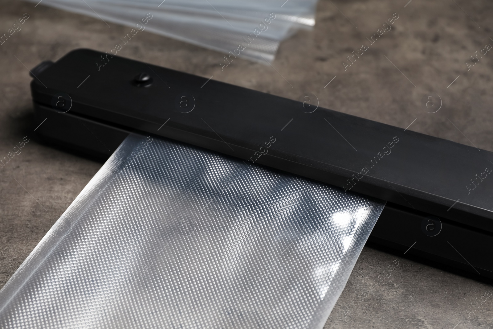 Photo of Sealer for vacuum packing with plastic bag on grey table, closeup