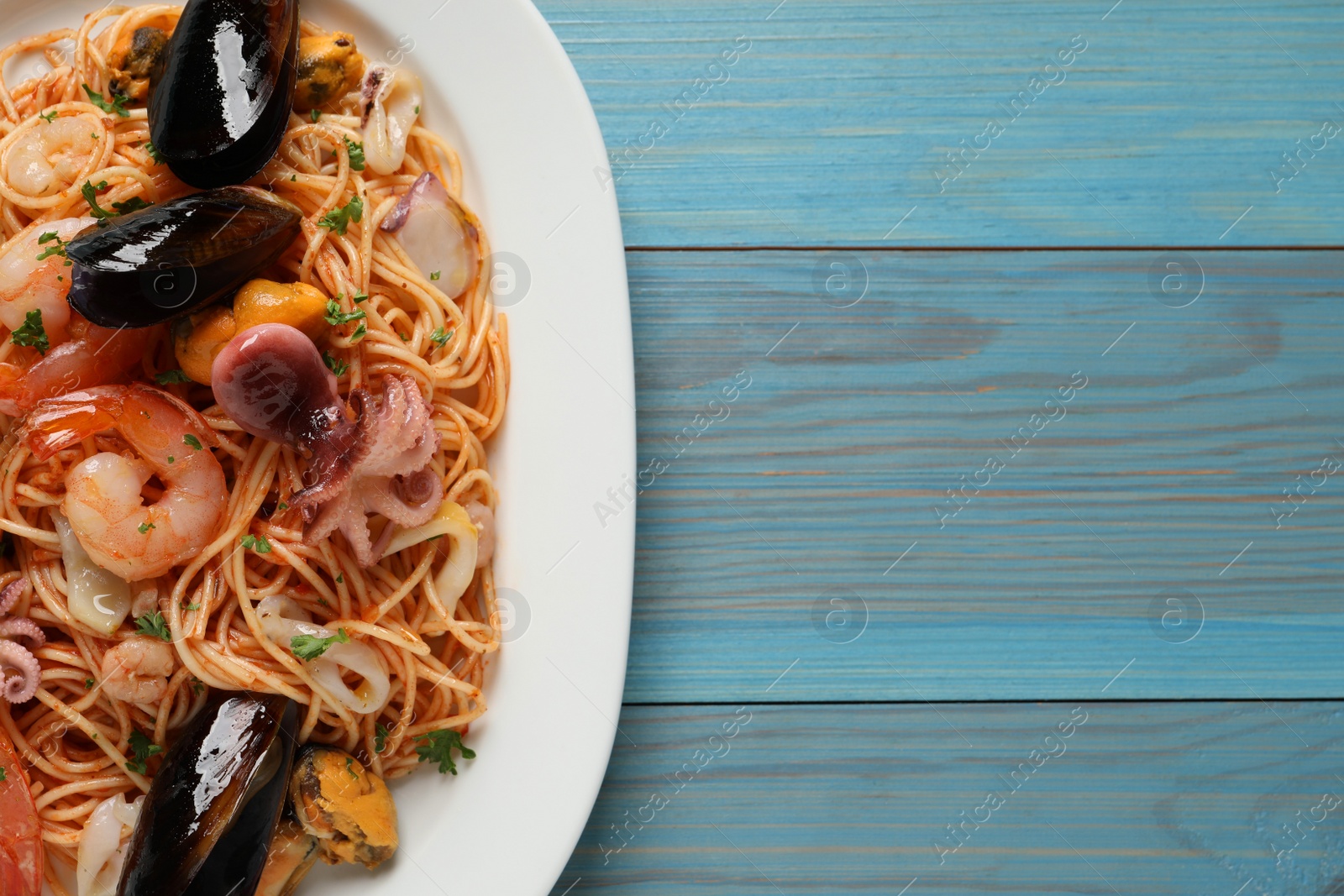 Photo of Delicious spaghetti with seafood served on turquoise wooden table, top view. Space for text