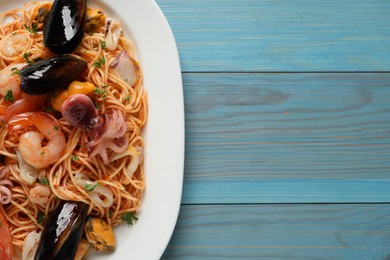 Delicious spaghetti with seafood served on turquoise wooden table, top view. Space for text