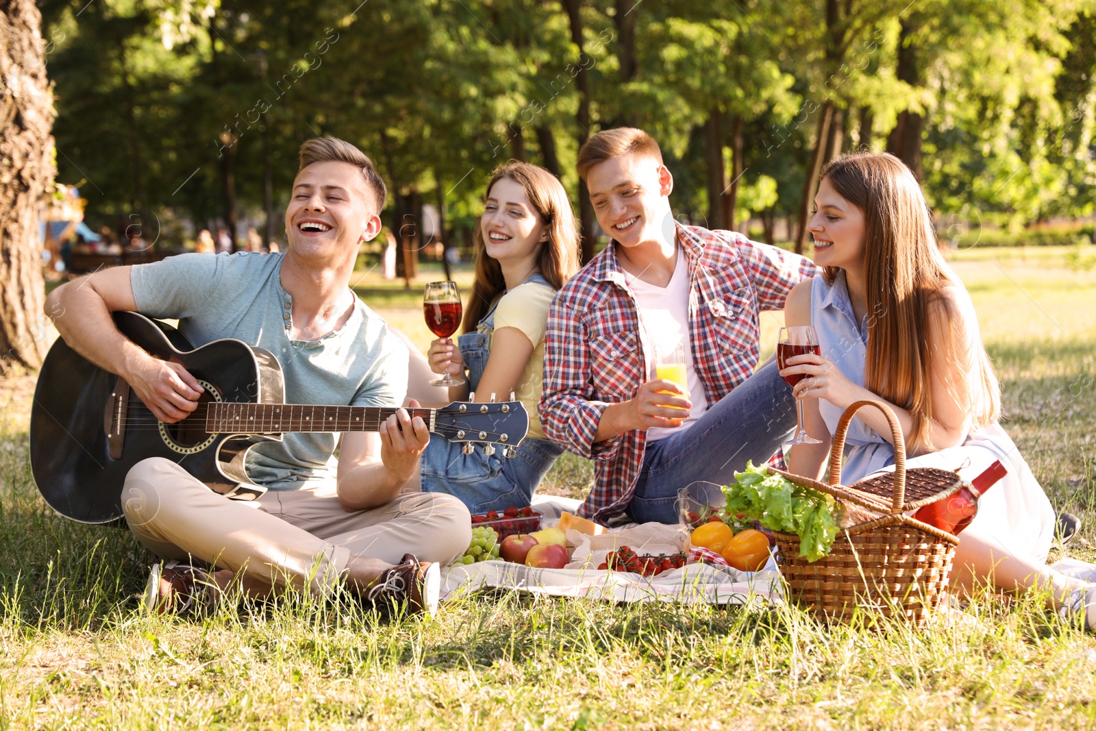 Photo of Young people enjoying picnic in park on summer day