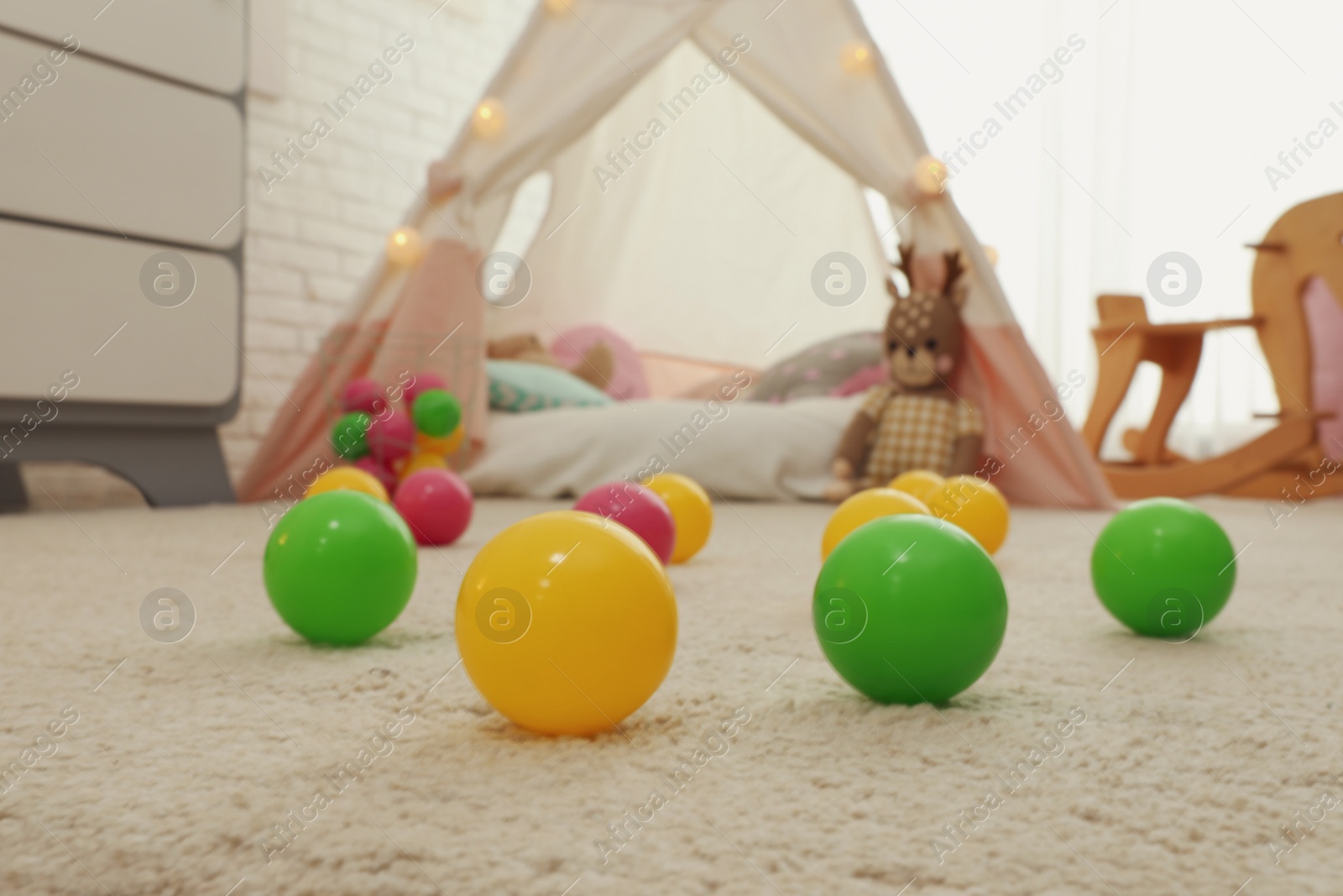 Photo of Bright toy balls near play tent on floor in child's room